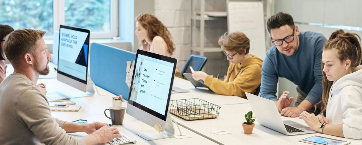 Personer som arbetar med datorer på ett stort kontorsbord.